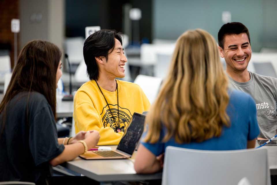 Students around a table interact in a college classroom